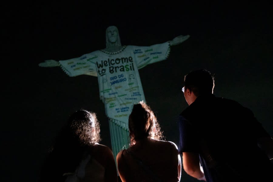 Fans look up at the Christ the Redeemer statue that is illuminated with a welcome message to American singer Taylor Swift, in Rio de Janeiro, Brazil, Thursday, Nov. 16, 2023. (AP Photo/Bruna Prado)