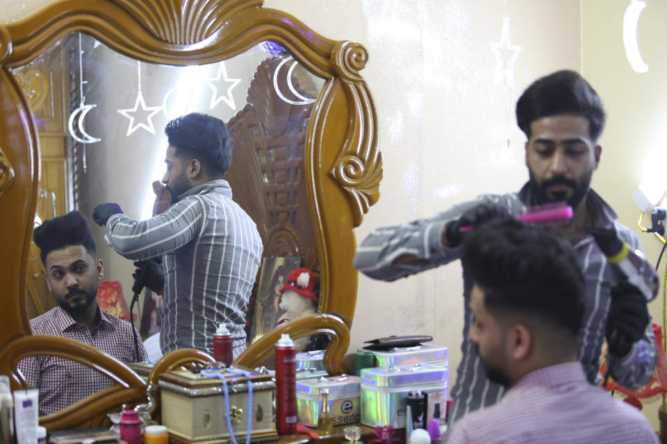 In this Thursday, April 9, 2020 photo, Ahmed Khaled al-Kaabi gets ready for his wedding in Najaf, Iraq, hardest hit town by coronavirus in the country with government banned large public gatherings. Unwilling to postpone the wedding, al-Kaabi asked the local security forces to help him wed his beloved. The police responded by providing the groom vehicles blasting music to bring his bride to the family home for a small celebration of just six people. (AP Photo/Anmar Khalil)