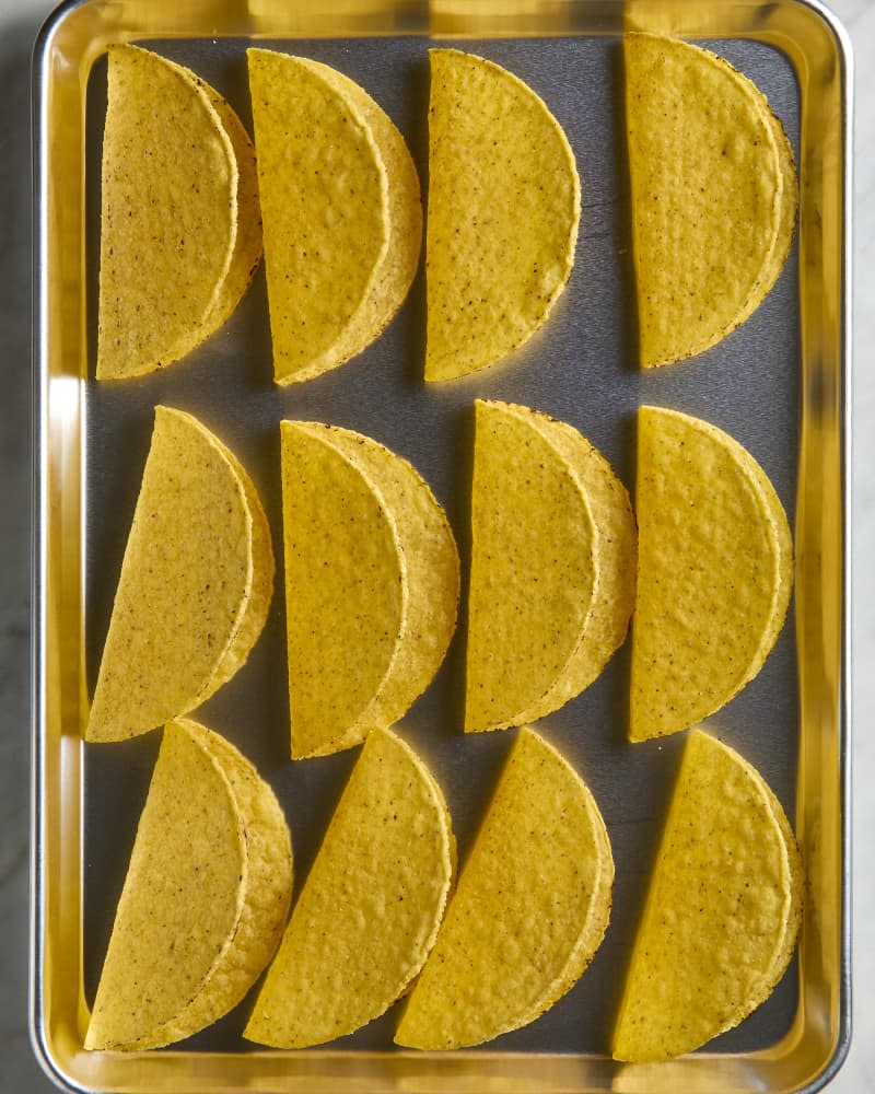 overhead shot of 12 hard taco shells on a baking sheet