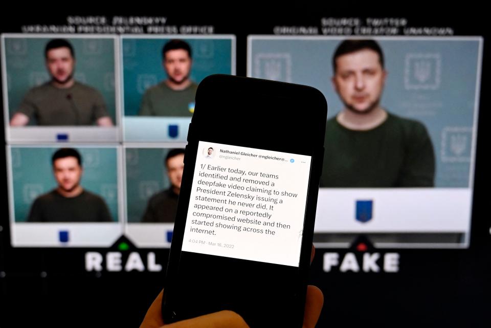 This illustration photo taken on January 30, 2023 shows a phone screen displaying a statement from the head of security policy at META with a fake video (R) of Ukrainian President Volodymyr Zelensky calling on his soldiers to lay down their weapons shown in the background, in Washington, DC. Chatbots spouting falsehoods, face-swapping apps generating fake porn and cloned voices defrauding companies of millions -- governments are scrambling to regulate AI-powered deepfakes widely feared to be a misinformation super spreader. (Photo by OLIVIER DOULIERY / AFP) (Photo by OLIVIER DOULIERY/AFP via Getty Images)