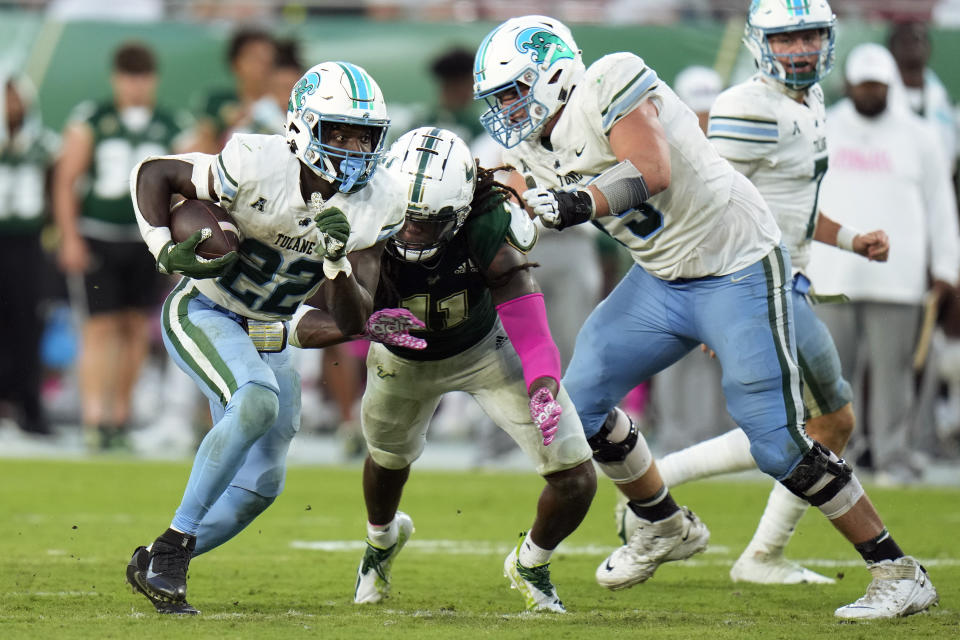 Tulane running back Tyjae Spears (22) heads upfield as offensive lineman Joey Claybrook (79) puts a block on South Florida linebacker Dwayne Boyles (11) during the second half of an NCAA college football game Saturday, Oct. 15, 2022, in Tampa, Fla. (AP Photo/Chris O'Meara)
