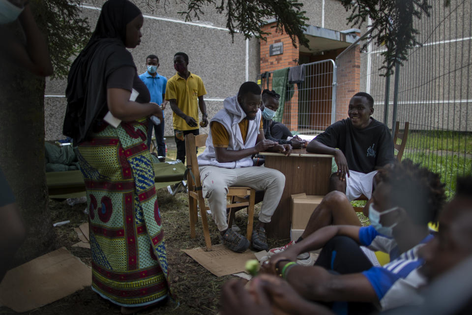 Migrants from Cameroon, Nigeria and Sierra Leone sit outside a school building at the refugee camp at the refugee camp in the village of Verebiejai, some 145km (99,1 miles) south from Vilnius, Lithuania, Sunday, July 11, 2021. Migrants at the school in the village of Verebiejai, about 140 kilometers (87 miles) from Vilnius, haven't been allowed to leave the premises and are under close police surveillance. Some have tested positive for COVID-19 and have been isolated in the building. (AP Photo/Mindaugas Kulbis)