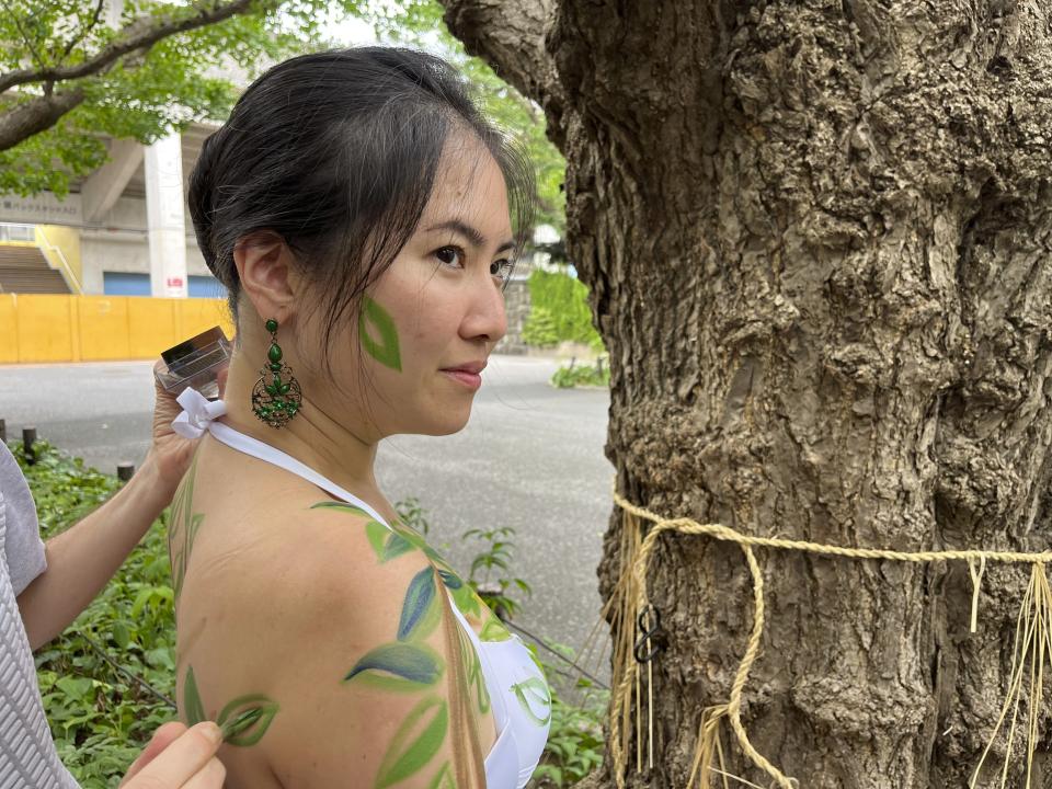 Miho Nakashima has her body painted like a tree by artist Andy Boerger during a public protest on Sunday, Aug. 27, 2023, to point out that 100-year-old trees in the Jingu Gaien park area in Tokyo, Japan, could be cut down under a disputed development plan. (AP Photo/Stephen Wade)