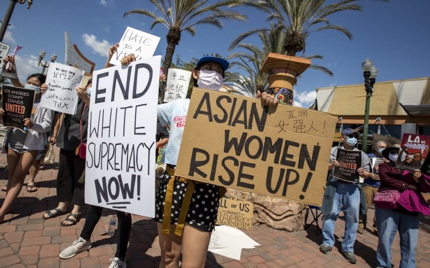 ALHAMBRA, CA - MARCH 21: Tina Zeng, 31, of Alhambra, holds two signs as she and other demonstrators gather to speak out and protest racism on Garfield Ave. on Sunday, March 21, 2021 in Alhambra, CA. (Brian van der Brug / Los Angeles Times)