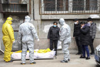 FILE - In this Feb. 1, 2020, file photo, funeral home workers remove the body of a person suspect to have died from a virus outbreak from a residential building in Wuhan in central China's Hubei Province. The Chinese city of Wuhan is looking back on a year since it was placed under a 76-day lockdown beginning Jan. 23, 2020. (Chinatopix via AP, File)