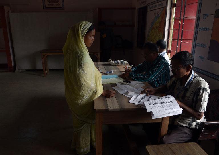 Indian election officials check the details of a voter at a polling booth in Dibrugarh on April 7, 2014