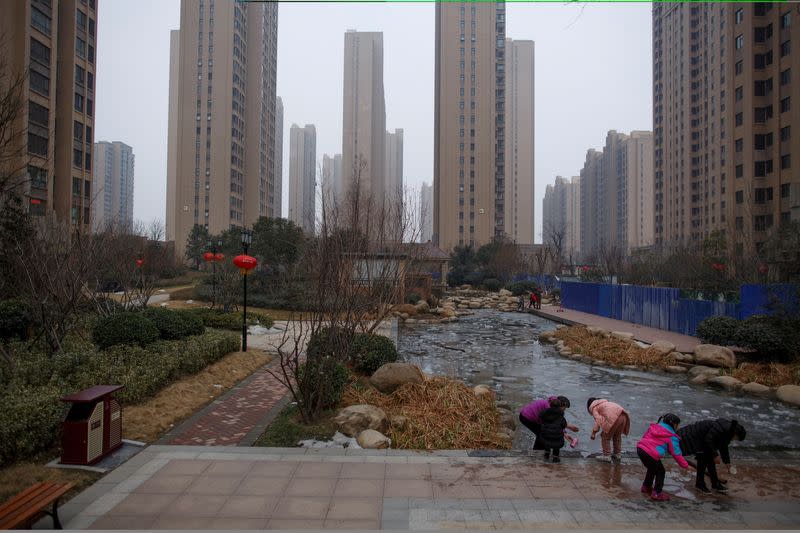 FILE PHOTO: People play with ice floats at a pond in the compound of a apartment complex in Zhengzhou
