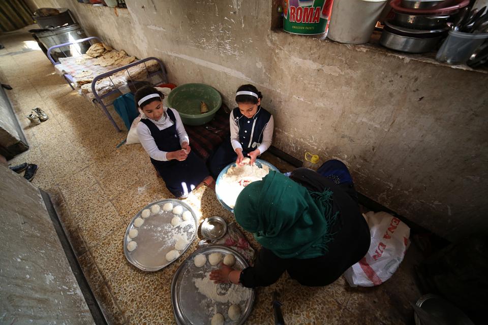 In this March 18, 2019 photo, Um Yusuf, a widow of an Islamic State group militant, and her daughters make bread to sell, in Mosul, Iraq. Thousands of Iraqi families face crushing social and legal discrimination -- all because of the choices their male relatives made under the Islamic State group’s rule. Um Yusuf and her seven children were left to shoulder the stigma of her husband's IS affiliation. She cannot get social assistance, and her teenage son Omar is being turned away from jobs. (AP Photo/Farid Abdulwahed)