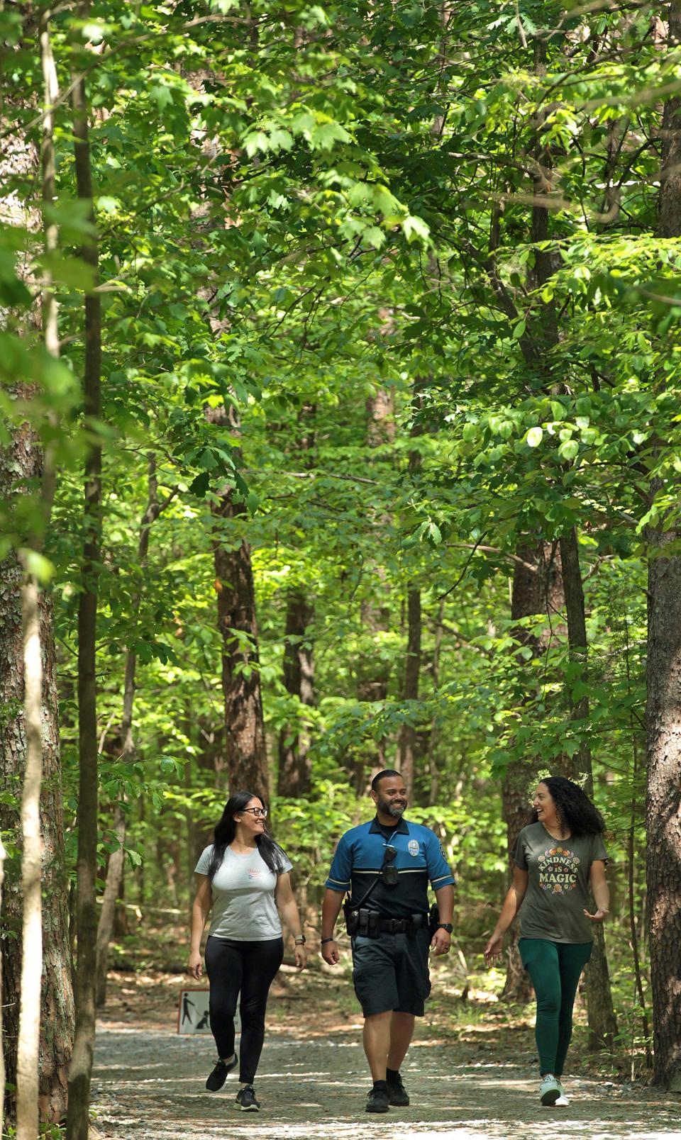 Yesenia Sanchez Tremba, Officer Alvaro Jaimes and Vivianette Ortiz walk on the trail at Crowders Mountain State Park Tuesday morning, May 3, 2022.