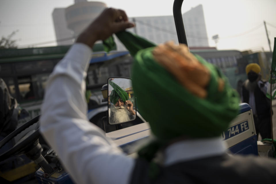 Jagir Singh, 71, looks into the mirror of a tractor as he ties his turban before joining fellow protesters protesting against new farm laws at the Delhi-Haryana state border, India, Tuesday, Dec. 1, 2020. Instead of cars, the normally busy highway on the outskirts of New Delhi that connects most northern Indian towns to the capital is filled with tens of thousands of protesting farmers, many wearing colorful turbans. It’s a siege of sorts and the mood among the protesting farmers is boisterous. Their rallying call is “Inquilab Zindabad” (“Long live the revolution”). (AP Photo/Altaf Qadri)