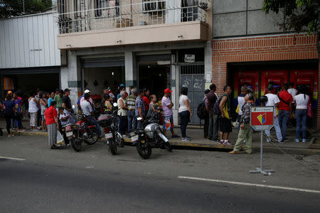 People line up to withdraw cash from an automated teller machine (ATM) outside a Banco de Venezuela branch in Caracas, Venezuela November 25, 2016. REUTERS/Marco Bello