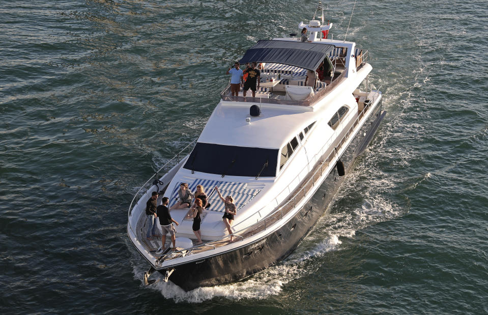 Tourists party on a yacht in Dubai, United Arab Emirates, Tuesday, Jan. 12, 2021. Since becoming one of the world's first destinations to open up for tourism, Dubai has promoted itself as the ideal pandemic vacation spot. With peak tourism season in full swing, coronavirus infections are surging to unprecedented heights, with daily case counts nearly tripling in the past month, but in the face of a growing economic crisis, the city won't lock down and can't afford to stand still. (AP Photo/Kamran Jebreili)