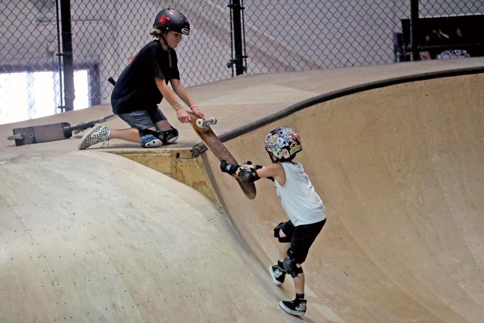 Noah Juncaj 11, of Royal Oak, uses a skateboard to help Kole Alberts, 8, of Frankenmuth, out of the bowl during the skate clinic held at Modern Skate Park on Monday, July 10, 2023. 