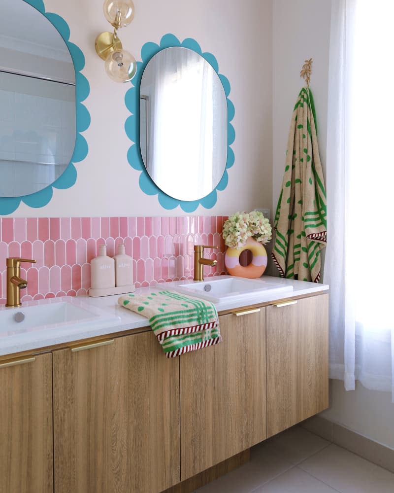 White and pink bathroom with blue "petals" around each mirror over double sink