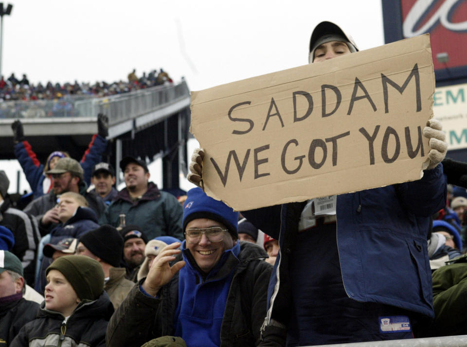 A fan at the NFL football game between the Jacksonville Jaguars and the New England Patriots in Foxboro, Massachusetts December 14, 2003 holds a sign celebrating the capture former Iraqi leader Saddam Hussein near his hometown of Tikrit. REUTERS/Brian Snyder  BS