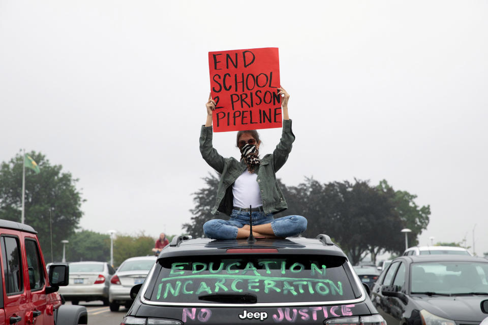 Image: A protester sits on top of a car after a caravan protest in support of a Black Groves High School student, who was jailed due to a probation violation of not keeping up with her online schoolwork, (Emily Elconin / Reuters)