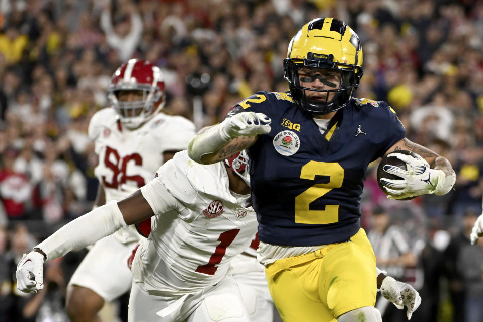 Michigan running back Blake Corum (2) runs in for a touchdown past Alabama defensive back Kool-Aid McKinstry (1) during overtime at the Rose Bowl CFP NCAA semifinal college football game Monday, Jan. 1, 2024, in Pasadena, Calif. (AP Photo/Kyusung Gong)