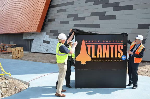 The new logo for the "Space Shuttle Atlantis" exhibit is unveiled by astronaut Jon McBride (left), Delaware North President Rick Abramson and Bill Moore, chief operating officer of the Kennedy Space Center Visitor Complex in Florida on Feb. 21,