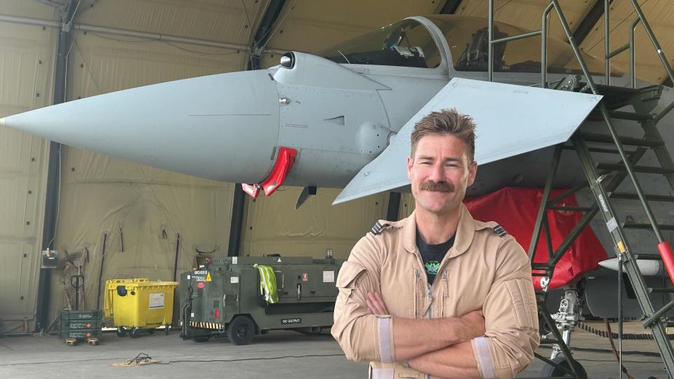 Flt Lt Charlie Tagg in front of a plane, in a hangar