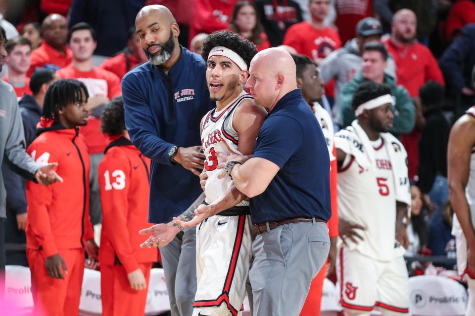 St. John's Red Storm guard Andre Curbelo (3) is taken off the court by Coordinator of Basketball Operations, Zendon Hamilton (l) and Strength and Conditioning Coach, Brandon Kuhn (r), after he was ejected in the second half against the Seton Hall Pirates