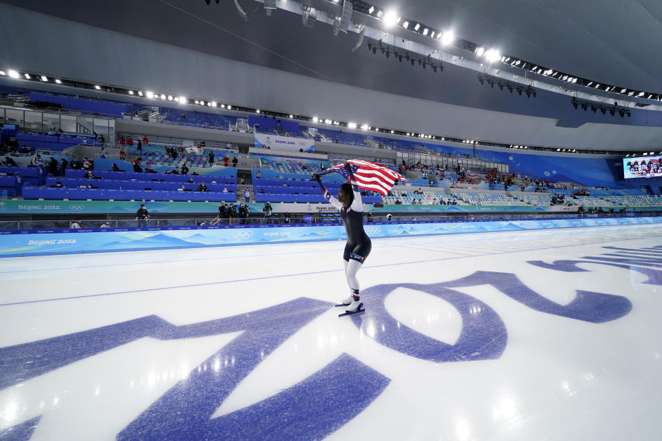 Erin Jackson of the United States carries an American flag across the ice after winning the gold medal in the speedskating women's 500-meter race at the 2022 Winter Olympics, Sunday, Feb. 13, 2022, in Beijing. (AP Photo/Ashley Landis)