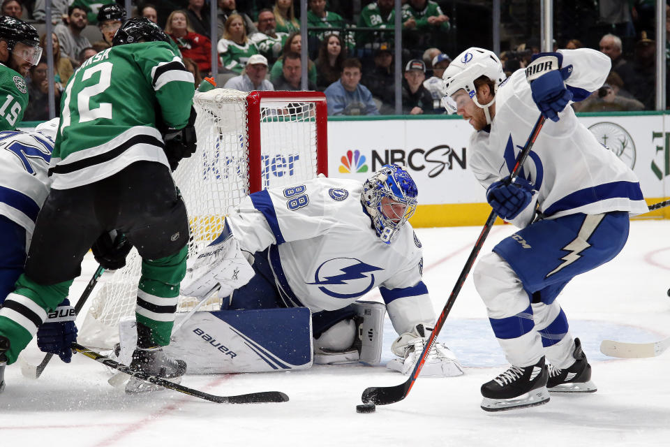 Tampa Bay Lightning center Brayden Point, right, clears the puck in front of goaltender Andrei Vasilevskiy, center, and Dallas Stars center Radek Faksa, left, during the first period of an NHL hockey game in Dallas, Monday, Jan. 27, 2020. (AP Photo/Ray Carlin)