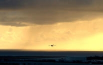 FILE — In this April 6, 2020 file photo, a plane lands as the sun sets over the international airport in Honolulu. Hawaii officials are facing pressure to increase COVID-19 testing for travelers. The islands are weathering a record surge and federal guidelines are being changed to require negative virus tests from both vaccinated and unvaccinated travelers to the U.S. State leaders have resisted implementation of a two-test policy for arriving travelers despite evidence that more COVID-19 testing would help reduce the spread of disease, especially in an isolated destination location like Hawaii. (AP Photo/Caleb Jones, File)