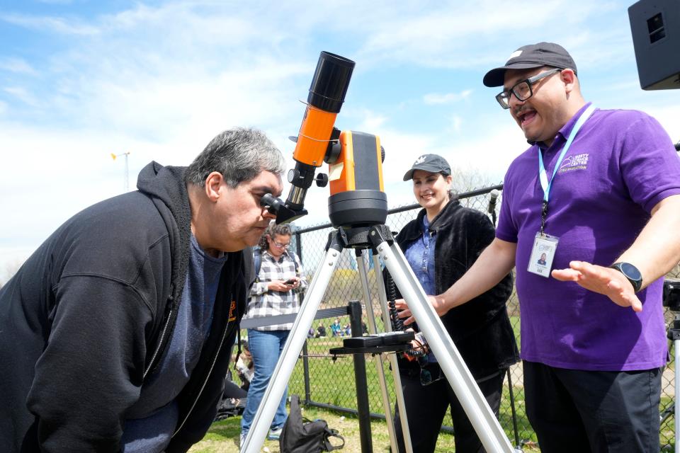 Mario Lisboa, looks through Ioptron Cube Telescope, beside, Liberty Science Center Sr. Manager of STEM Innovation, Alejandro Melendez, Monday, April 8, 2024, in Jersey City.