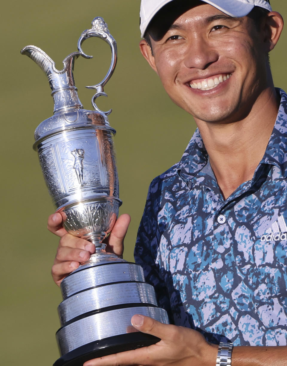 United States' Collin Morikawa holds up the claret jug trophy as he poses for photographers on the 18th green after winning the British Open Golf Championship at Royal St George's golf course Sandwich, England, Sunday, July 18, 2021. (AP Photo/Ian Walton)