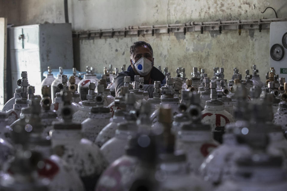 A hospital staff checks oxygen cylinders inside a hospital in Srinagar, Indian controlled Kashmir, Sunday, April 25, 2021. India’s crematoriums and burial grounds are being overwhelmed by the devastating new surge of infections tearing through the populous country with terrifying speed, depleting the supply of life-saving oxygen to critical levels and leaving patients to die while waiting in line to see doctors. (AP Photo/Mukhtar Khan)