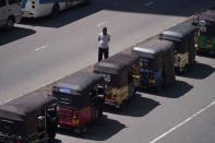 A man stands next to his autorickshaw as waits to buy gasoline near a fuel station in Colombo, Sri Lanka, Thursday, May 19, 2022. (AP Photo/Eranga Jayawardena)