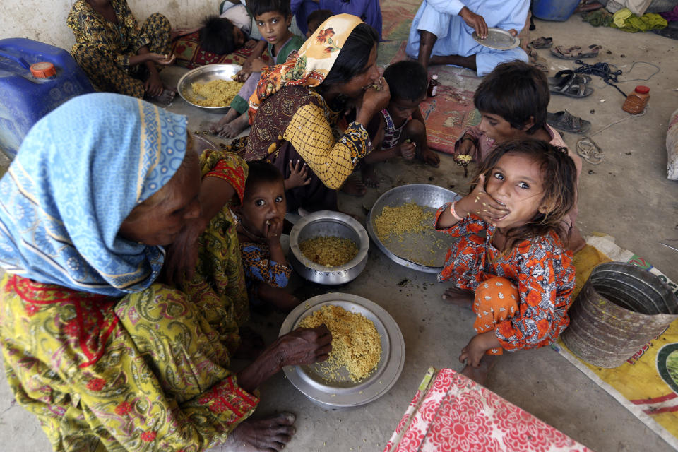 Victims of the unprecedented flooding from monsoon rains receive relief food organized by the Alkhidmat Foundation, in Jaffarabad, a district of Pakistan's southwestern Baluchistan province, Monday, Sept. 5, 2022. The U.N. refugee agency rushed in more desperately needed aid Monday to flood-stricken Pakistan as the nation's prime minister traveled to the south where rising waters of Lake Manchar pose a new threat. (AP Photo/Fareed Khan)