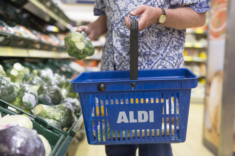 A customer picks a bunch of Broccoli from the vegetable display at Aldi