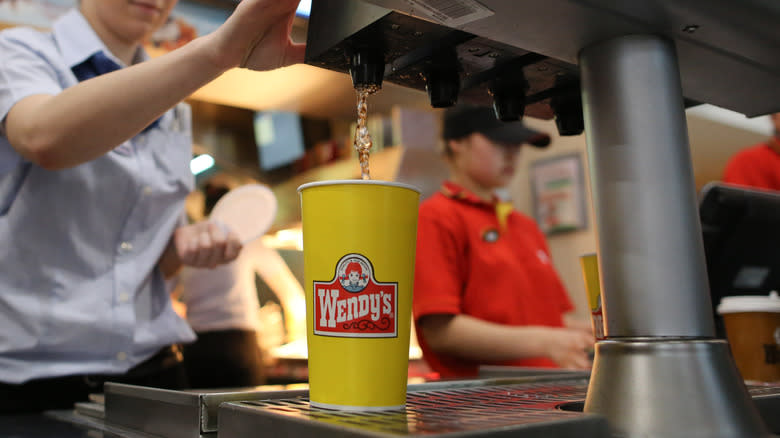 Employee operating soda machine with Wendy's cup