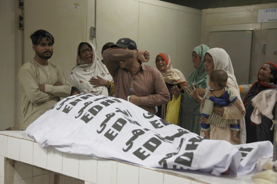 People mourn next to the body of their family member, who was died in the stampede, at a morgue, in Karachi, Pakistan, Friday, March 31, 2023. Several people were killed in the deadly stampede at a Ramadan food distribution center outside a factory in Pakistan's southern port city of Karachi, police and rescue officials said. (AP Photo/Ikram Suri)