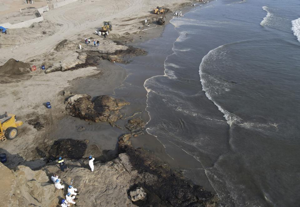 Workers clean up an oil spill at Cavero beach in Ventanilla, Callao, Peru, Monday, Jan. 17, 2022. Unusual high waves that authorities attribute to the eruption of the undersea volcano in Tonga caused the spill on the Peruvian Pacific coast as a ship was loading oil into La Pampilla refinery on Sunday. (AP Photo/Martin Mejia8