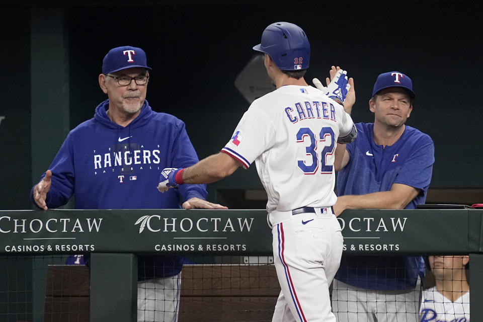 Texas Rangers' Evan Carter (32) is congratulated on his two-run home run by manager Bruce Bochy, left, and hitting coach Tim Hyers, right, in the sixth inning of a baseball game against the Boston Red Sox Wednesday, Sept. 20, 2023, in Arlington, Texas. Leody Taveras also scored on the shot. (AP Photo/Tony Gutierrez)