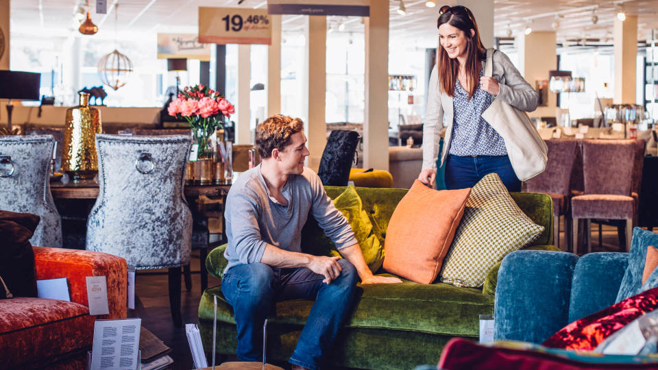 Young women out shopping with her husband in a furniture shop.