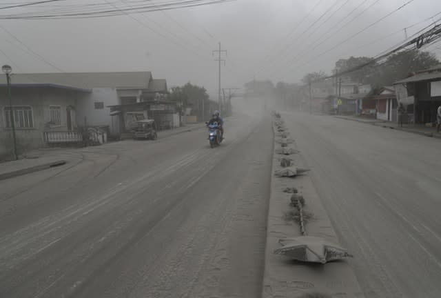 A man negotiates a road covered with ash spewed from Taal volcano in Lemery, Batangas, southern Philippines