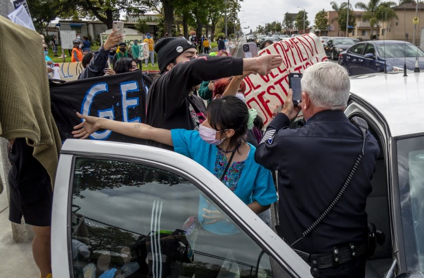 BELL, CA - APRIL 24, 2021: Activists block a Bell police officer from videotaping them while they demonstrated in front of Bell Mobile Home Park to protest the city selling the mobile home park on April 24, 2021 in Bell, California.(Gina Ferazzi / Los Angeles Times)