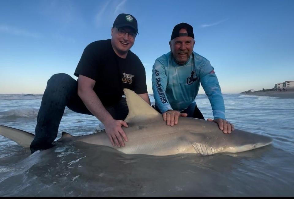 Kevin (left), from Massachusetts, with one of FOUR sharks he brought to shore with NSB Shark Hunters.