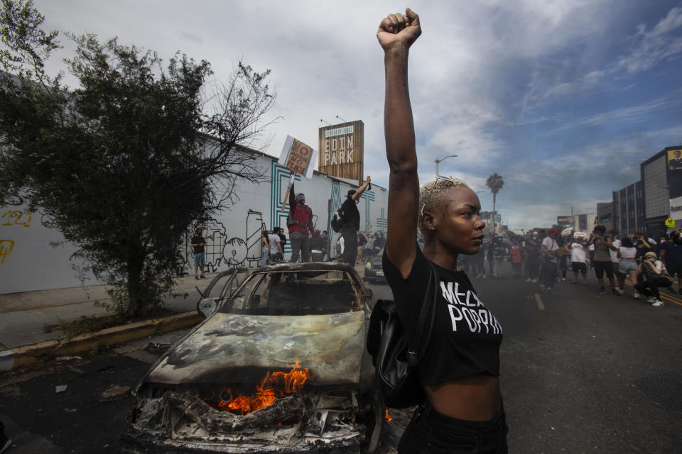 A protester raises her fist in the air next to a burning police vehicle in Los Angeles, May 30, 2020, during a demonstration over the death of George Floyd. The image was part of a series of photographs by The Associated Press that won the 2021 Pulitzer Prize for breaking news photography. (AP Photo/Ringo H.W. Chiu)