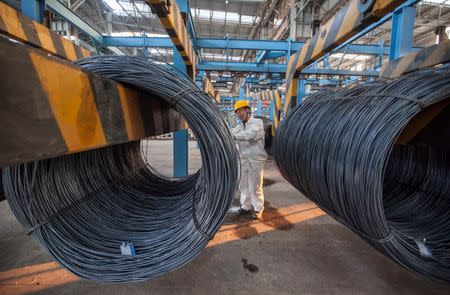 An employee inspects newly-made steel coils at a steel plant in Lianyungang, Jiangsu province October 11, 2014. REUTERS/China Daily