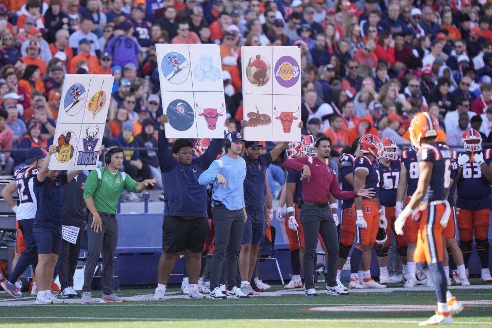 FILE - Members of the Illinois football team send in signals during an NCAA college football game against Wisconsin Saturday, Oct. 21, 2023, in Champaign, Ill. NCAA investigators interviewed members of Michigan football coach Jim Harbaugh’s staff about a sign-stealing scheme on Wednesday, Oct. 25, 2023, a person familiar with the governing body’s visit told The Associated Press. The NCAA does not directly ban the stealing of signs, but there are rules against using electronic equipment to record an opponent’s signals and in-person, advanced scouting of future opponents in season. (AP Photo/Charles Rex Arbogast, File)