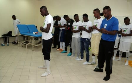 FILE PHOTO: Migrant workers pray before their final soccer match at the Workers' Cup in Doha, Qatar