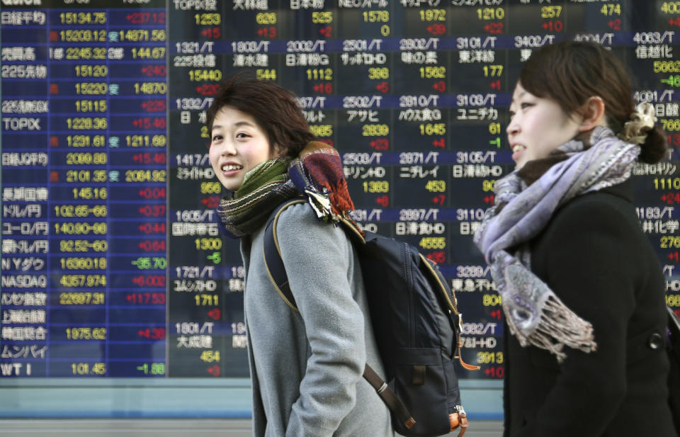 People walk by an electronic stock board of a securities firm in Tokyo, Thursday, March 6, 2014. Shares were mostly higher in Asia on Thursday as the standoff over Ukraine between Russia and the West continued to ease and the yen weakened. (AP Photo/Koji Sasahara)