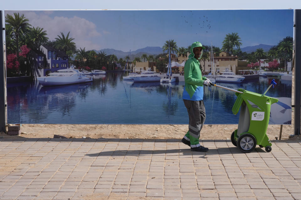 FILE - A municipal worker passes advertisements for tourism outside the convention center which will host the COP27 U.N. Climate Summit in Sharm el-Sheikh, Egypt, Friday, Nov. 4, 2022. (AP Photo/Peter Dejong, File)