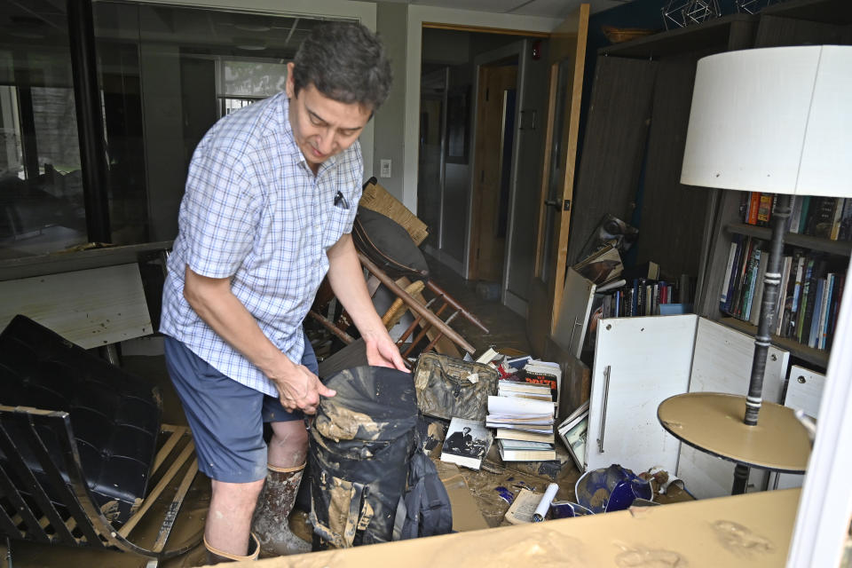 Will Anderson, Director of the Hindman Settlement School sorts through the mud covered objects in his office in Hindman, Ky., Friday, July 29, 2022. (AP Photo/Timothy D. Easley)