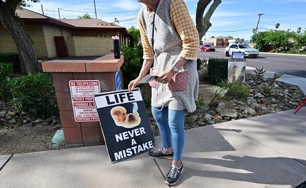 An anti-abortion rights advocate places a sign in front of an abortion clinic in Phoenix on April 18, 2024. <a href="https://www.gettyimages.com/detail/news-photo/longtime-pro-life-advocate-lynn-dyer-places-a-sign-that-news-photo/2149954349?adppopup=true" rel="nofollow noopener" target="_blank" data-ylk="slk:Frederic J. Brown/AFP via Getty Images;elm:context_link;itc:0;sec:content-canvas" class="link ">Frederic J. Brown/AFP via Getty Images</a>