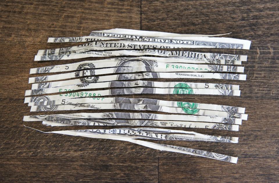 A shredded one dollar note on a wooden table